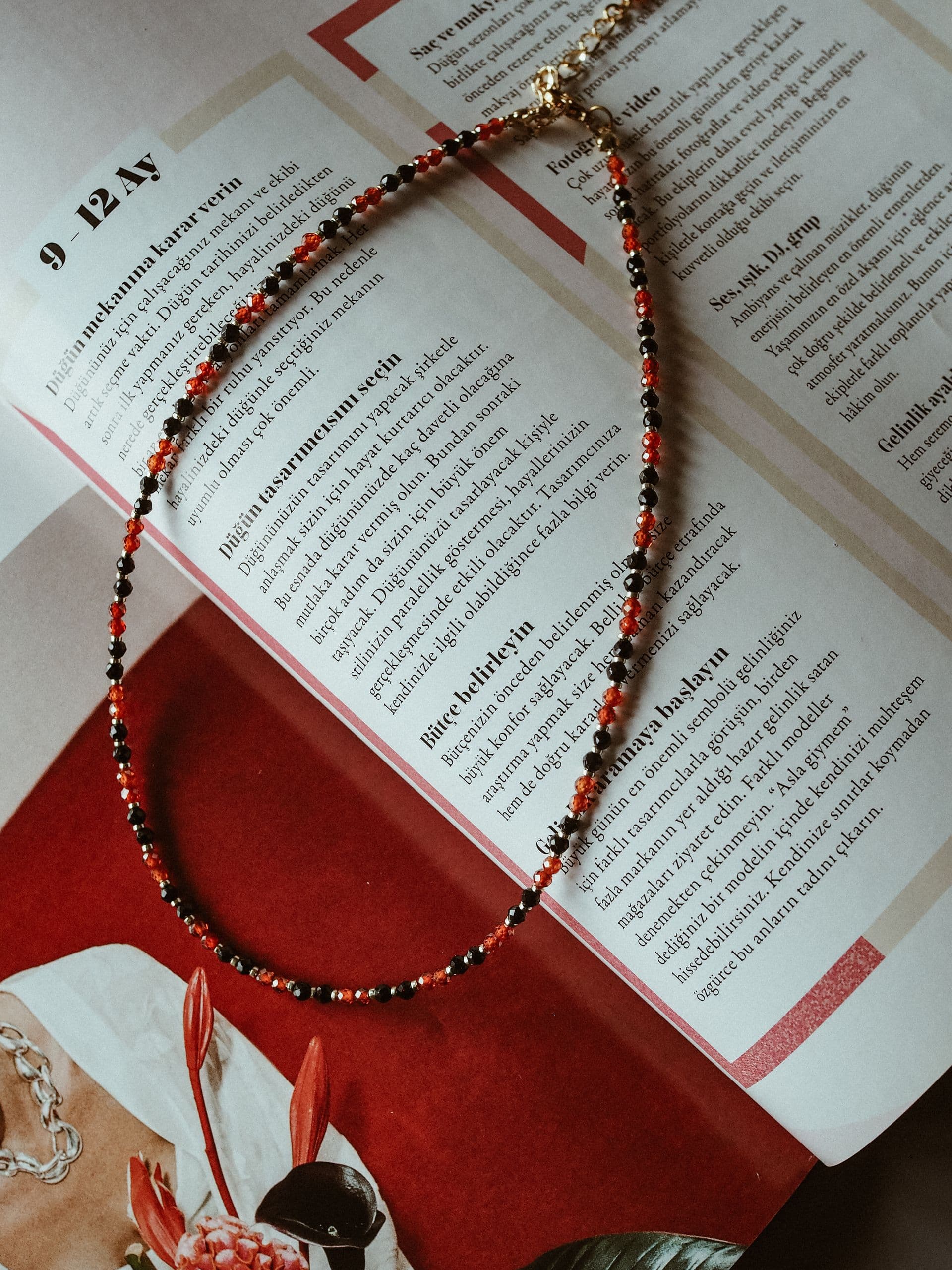 A beaded necklace laid across the open pages of a magazine