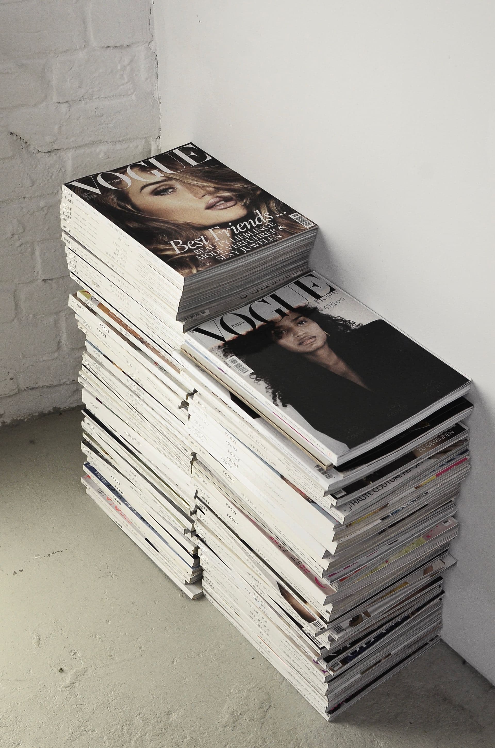 A tall stack of printed issues against a white wall