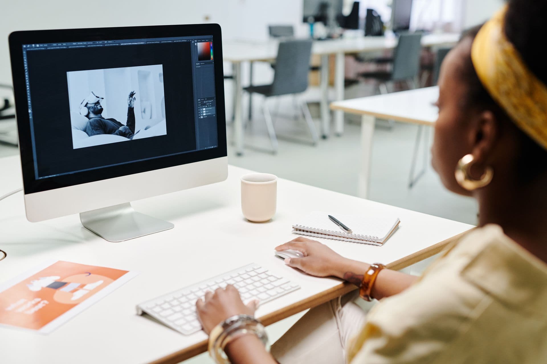 An editor retouches a photograph at her desk in a bright studio