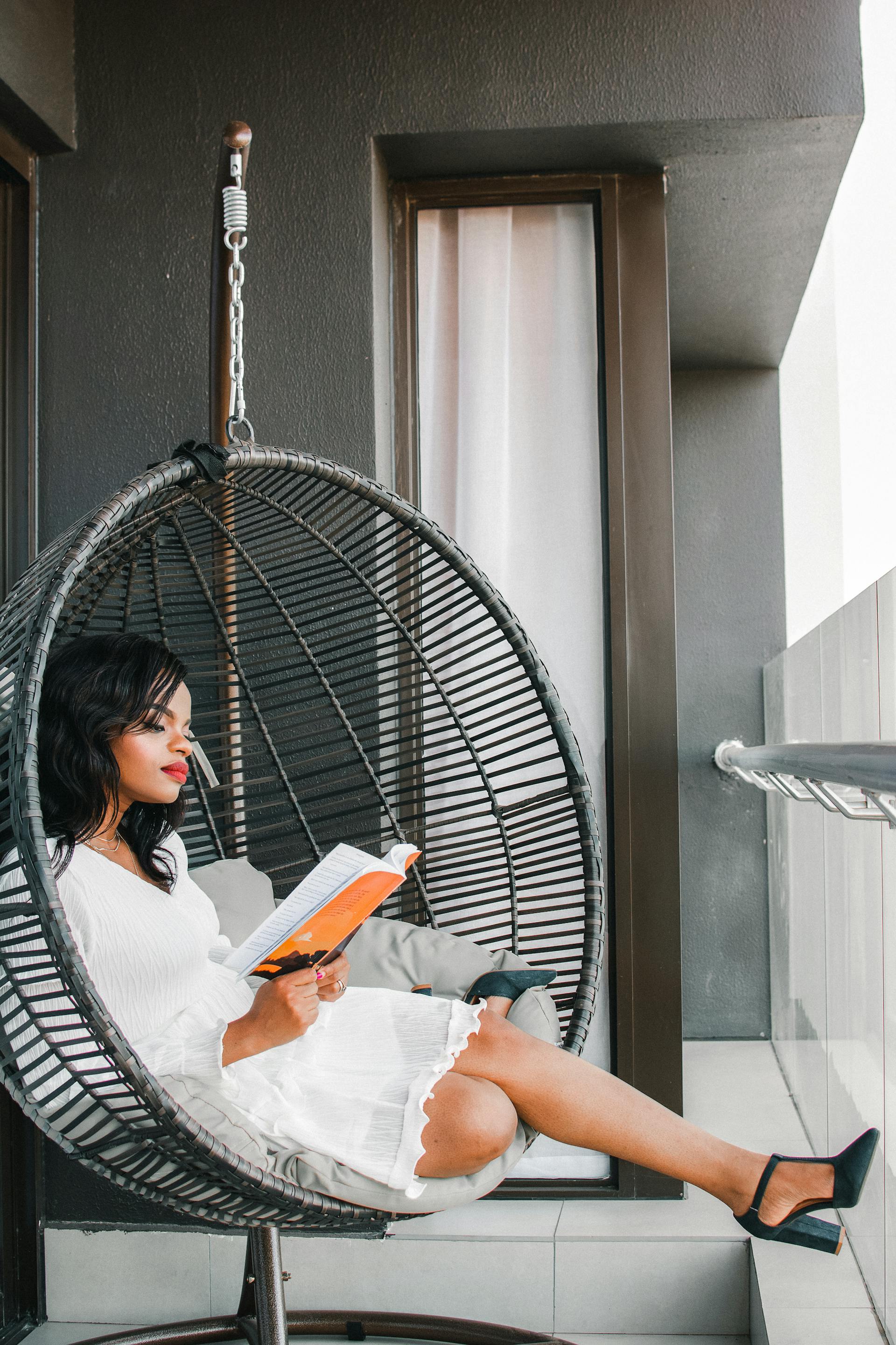 Reader in a hanging chair with an open magazine